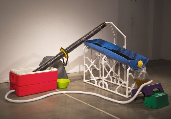 Conor Fields. Achaemedis Screw. 2014; cooler, 55 gallon drum, PVC, motor, charcoal, water, nylon tubing, water jug, step stool, bucket, wheel rim, bicycle tube; dimensions variable. Courtesy of the artist.